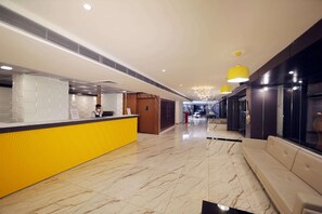 A hotel reception area with a marble floor, a reception desk, and a seating area with a sofa. - The Zinc By The Fern (Bengaluru)