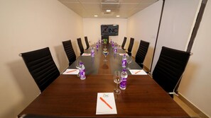 A conference room with a long table, black chairs, and a sign for The Zinc INC. - The Zinc By The Fern (Bengaluru)