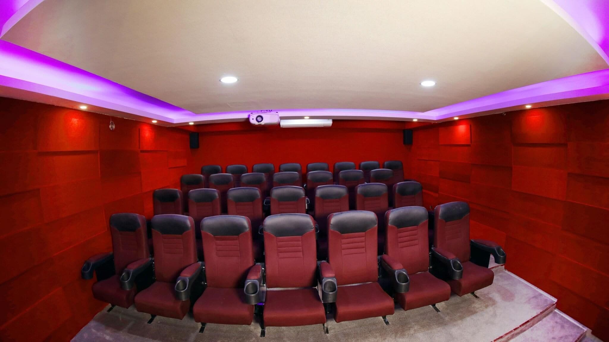 Un teatro con paredes rojas, varias filas de asientos e iluminación empotrada en el techo.