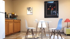 A compact kitchen with wooden cabinets, a white refrigerator, a coffee maker, and a small dining table with two chairs. - Large Private Oasis with Yard Space, Minutes to Downtown (San Jose)