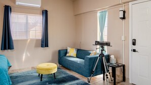A room with a blue sofa, a yellow ottoman, a tripod, and a white door. - Large Private Oasis with Yard Space, Minutes to Downtown (San Jose)
