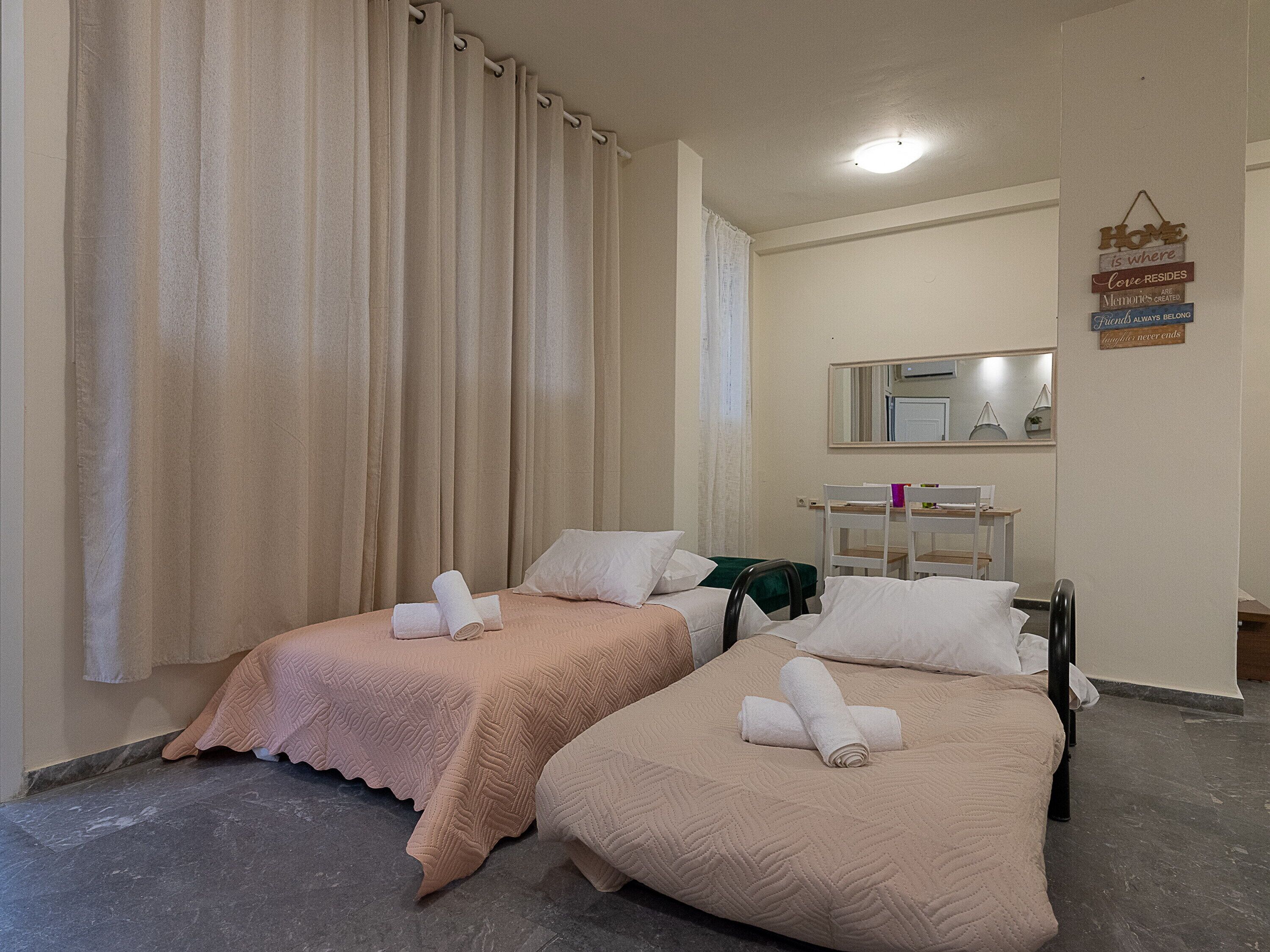 Quarto de hotel com duas camas, cada uma com uma toalha enrolada, um espelho sobre as camas e uma placa na parede.