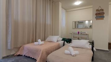 Quarto de hotel com duas camas, cada uma com uma toalha enrolada, um espelho sobre as camas e uma placa na parede.