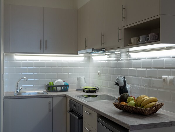 A modern kitchen with white cabinets, a stainless steel sink, and a fruit bowl on the counter.