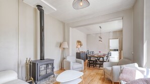 Ein modernes Wohnzimmer mit Kamin, weißen Sofas, einem Essbereich und einer Küche im Hintergrund.