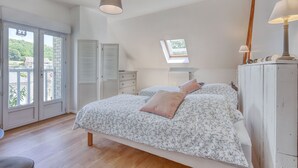 Ein Schlafzimmer mit einem Bett, Nachttischlampen, einem Fenster und Blick ins Freie.