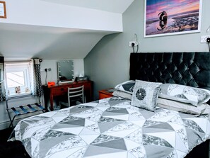 Relax in a stylish bedroom with a geometric-patterned bed, tufted headboard, and a large framed photograph.