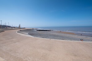 A beach promenade with a curved walkway, pebbles, and a view of the sea. - Seahawk Holiday Apartments (Thornton-Cleveleys)