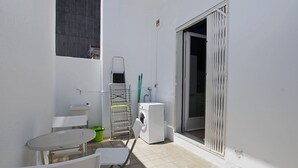 Un espacio al aire libre pequeño y cerrado con lavadora, pileta, mesa y sillas.