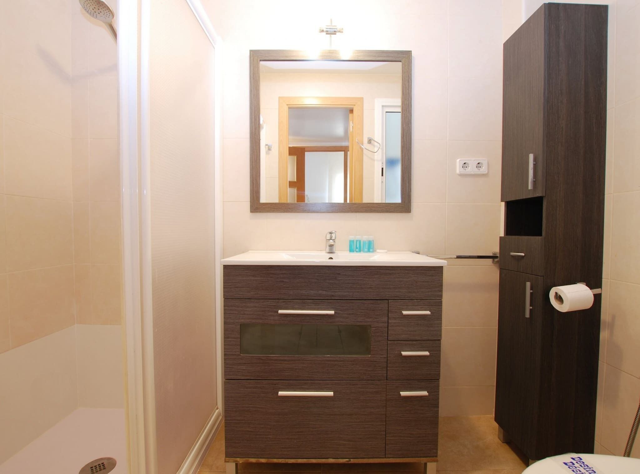 Un baño con tocador de madera oscura, un espejo y un inodoro.