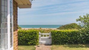 A pathway leading to a beach with a white gate, a brick wall, and a clear sky. - Downsview - large family home on the beach in Kingsdown (Deal)