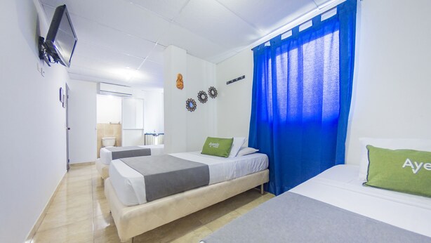 A hotel room with two beds, a television, and a bathroom in the background. - Hotel Puerto Vigia (Cartagena)
