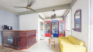 A reception area with a wooden desk, a yellow sofa, and vending machines. - Hotel Puerto Vigia (Cartagena)