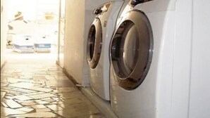 A laundry room with two front-loading washing machines and a tiled floor. - Hotel Puerto Vigia (Cartagena)