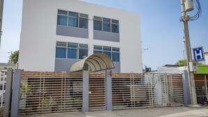 A modern building with a gated entrance, a covered waiting area, and a visible sign indicating a hotel. - Hotel Puerto Vigia (Cartagena)