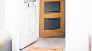 Une porte blanche avec un panneau en bois et un panneau en verre, un paillasson et le numéro « 30 » visible à travers le verre.