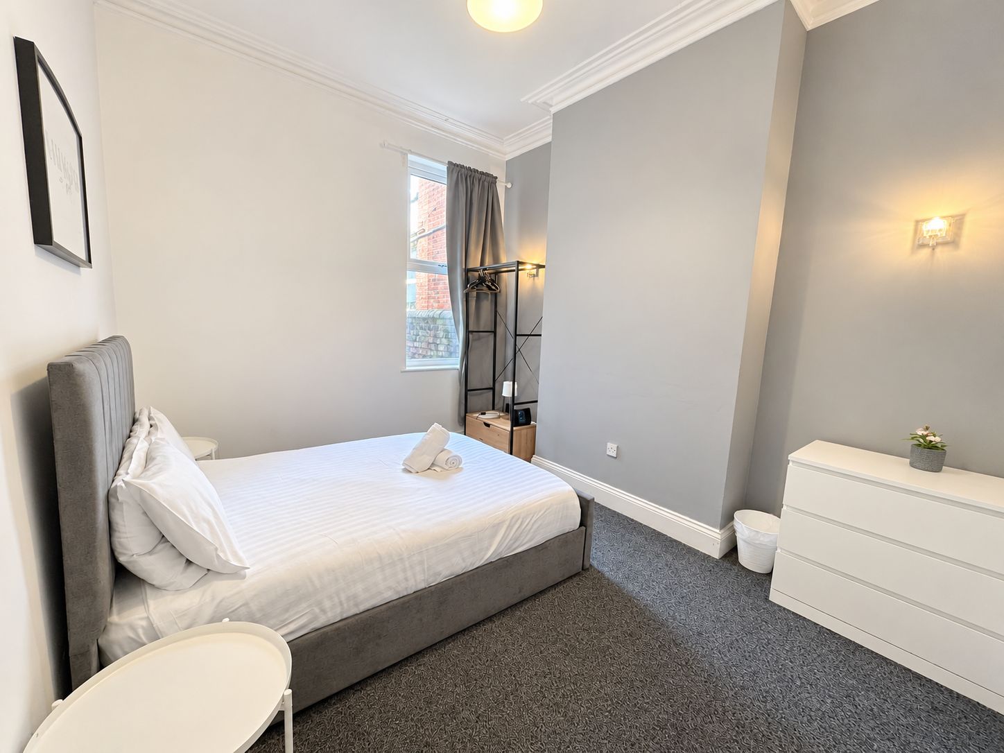 Ein modernes Schlafzimmer mit Bett, Nachttisch und Kommode.