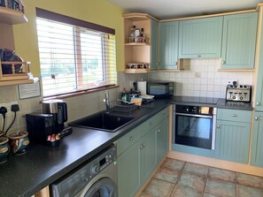 A kitchen with a washing machine, a microwave, a toaster, and a sink.