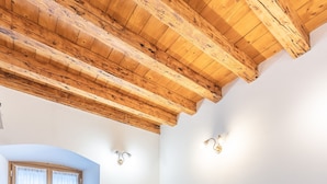 A dining area with a wooden table and benches, a wooden ceiling, and a sliding glass door. - Alla Regia (Vodo Cadore)