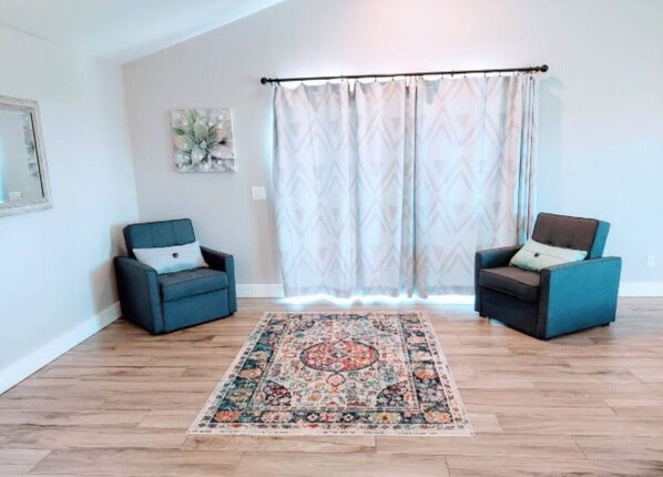 A room with two armchairs, a patterned rug, and a window with a curtain.