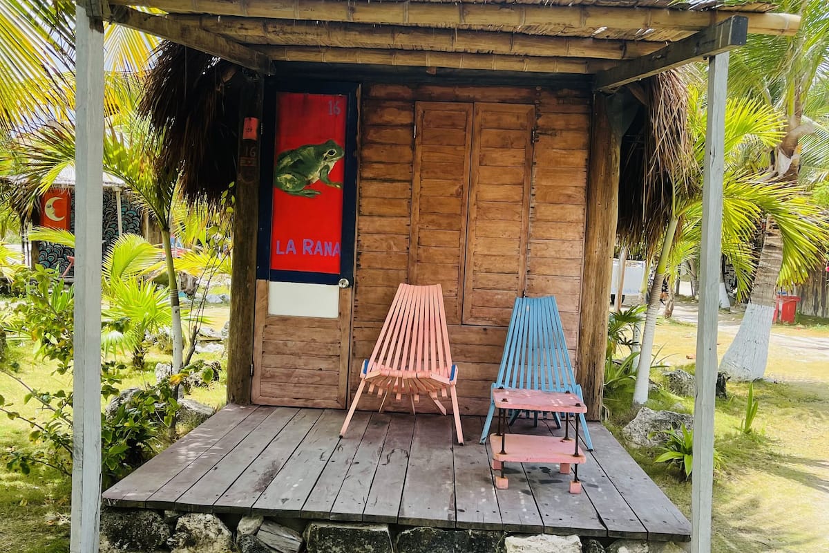 A wooden hut with a thatched roof, two wooden chairs, and a poster on the wall.
