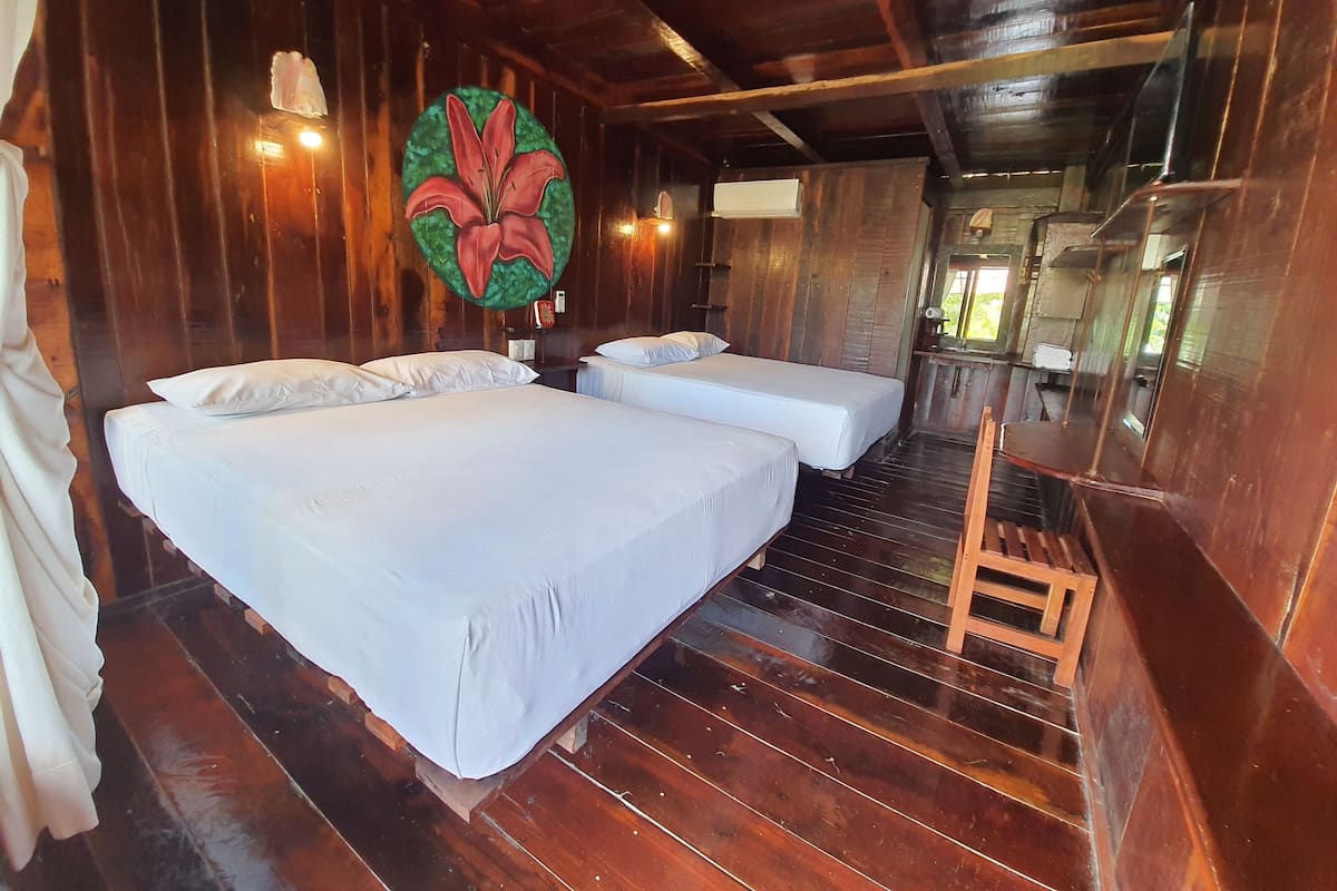 A wooden cabin with two beds, a wooden ladder, and a large floral artwork on the wall.
