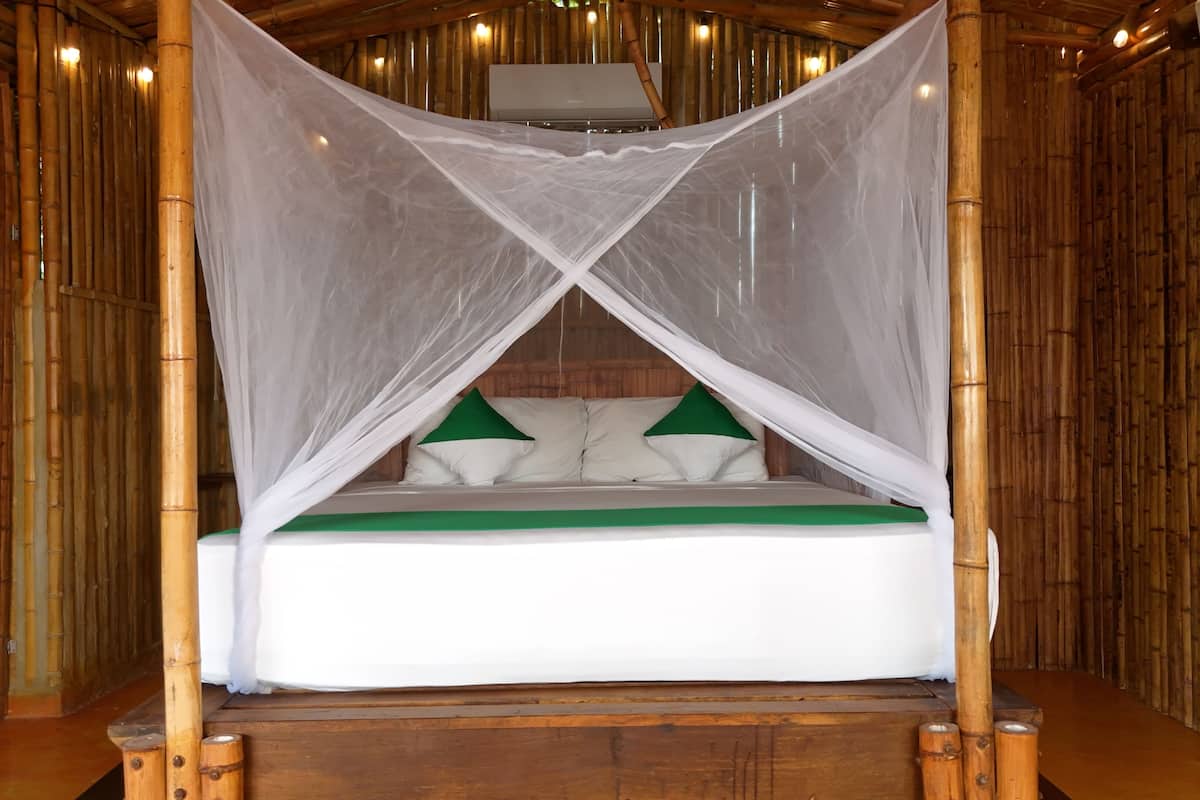 A bed with a canopy in a room with wooden walls and a ceiling fan.