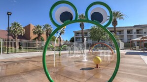 Ein Wasserspielbereich mit einer Frosch-Themen-Anlage, einer Fontäne und einem gelben Ball.