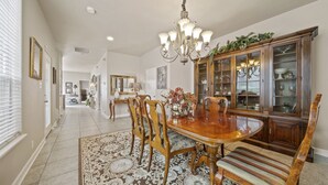 A dining room with a wooden table, chairs, a chandelier, and a cabinet with glass doors. - Ideally Located 3-Bedroom Townhouse (Tulsa)