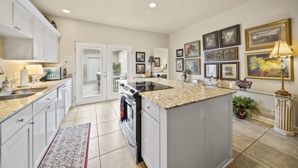 A modern kitchen with white cabinets, a granite countertop, and a built-in stove. - Ideally Located 3-Bedroom Townhouse (Tulsa)