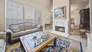 A spacious living room with a fireplace, a large window, and a cozy seating area. - Ideally Located 3-Bedroom Townhouse (Tulsa)