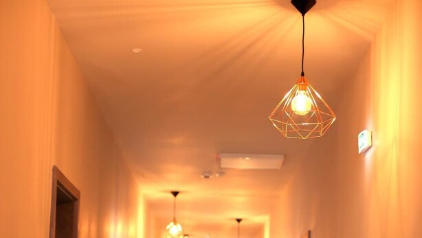 A hotel hallway with a polished wooden floor, recessed lighting, and a geometric pendant light fixture. - Lunii 6 Apartments (Brasov)