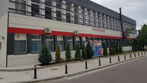 A modern building with a red and white facade, multiple windows, and a sign for 'Kronstadt'. - Lunii 6 Apartments (Brasov)