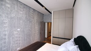 A modern bedroom with a large bed, grey textured walls, and a wardrobe with sliding doors. - Lunii 6 Apartments (Brasov)