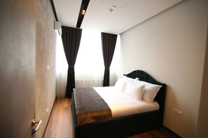 A bedroom with a bed, curtains, a radiator, and a ceiling light.
