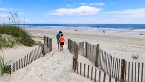 Ein sandiger Strand mit einer Holzlattenzaun, der zum Wasser führt.