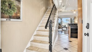 Eine Treppe mit schwarzer Geländer, die zu einem Küchenbereich mit einem Edelstahlherd und Blick ins Freie führt.