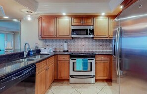 Una cucina moderna con mobili in legno, elettrodomestici in acciaio inossidabile e zoccolo paraschizzi in piastrelle.