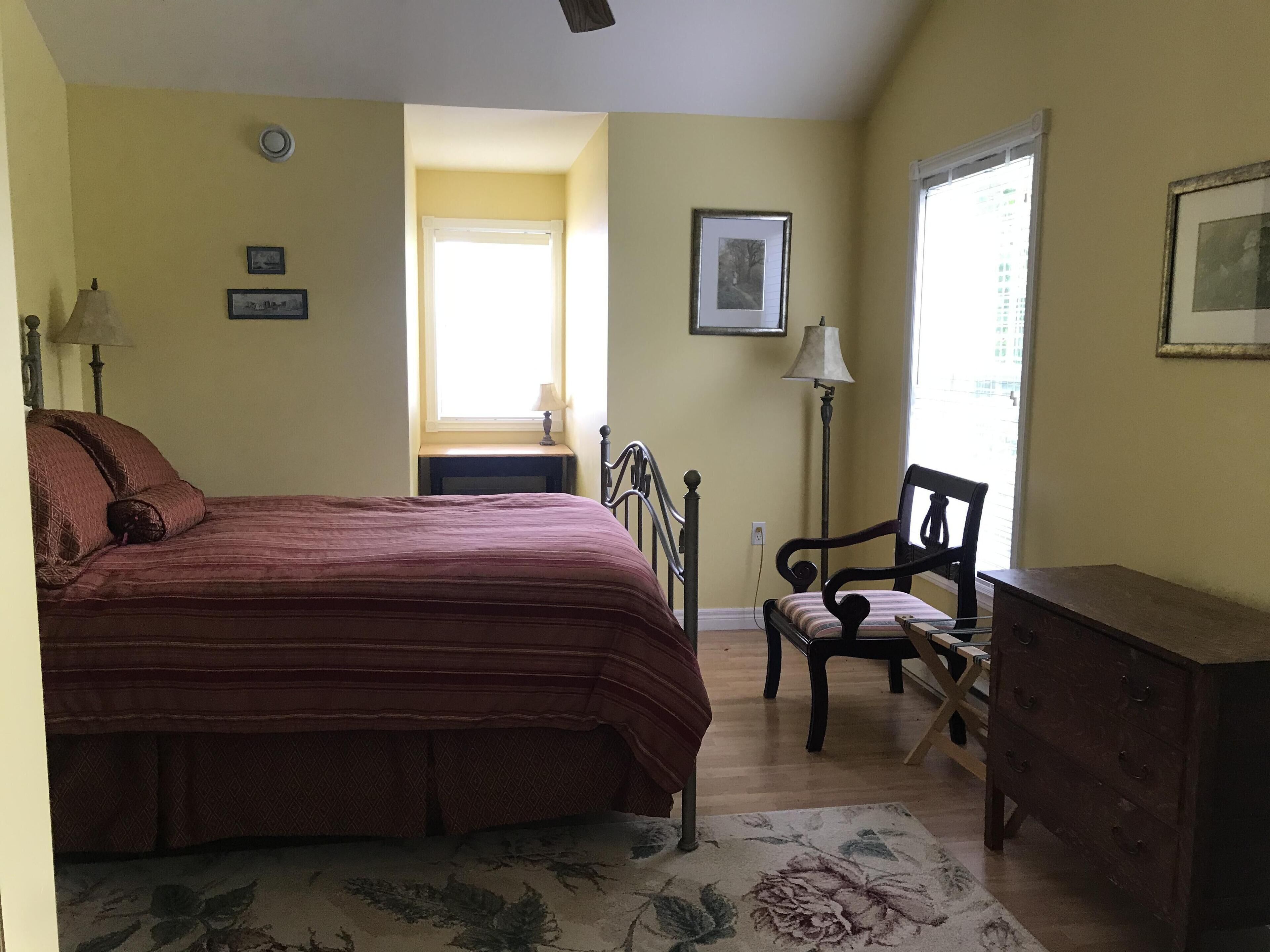 A bedroom with a bed, a chair, a dresser, and a window.