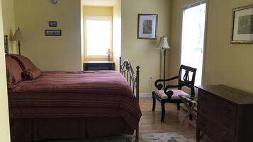 A bedroom with a bed, a chair, a dresser, and a window.