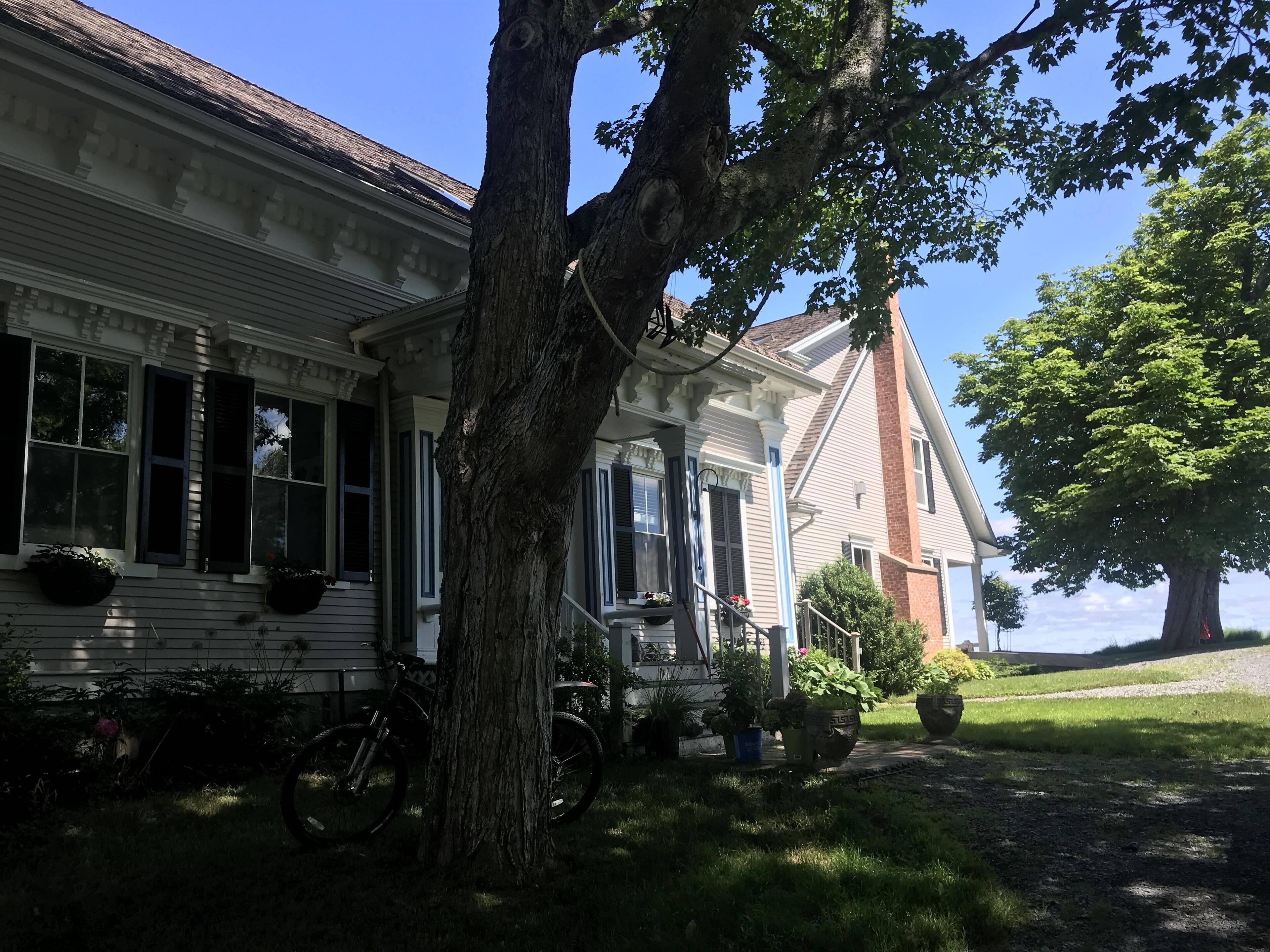 A traditional house with a porch, a bicycle, and potted plants.