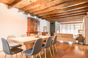 A spacious dining area with a wooden table and chairs, a built-in cabinet, and a stone wall.