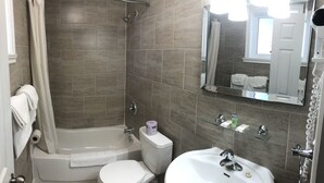 A bathroom with a bathtub, toilet, and sink. - Century motel (Cornwall)