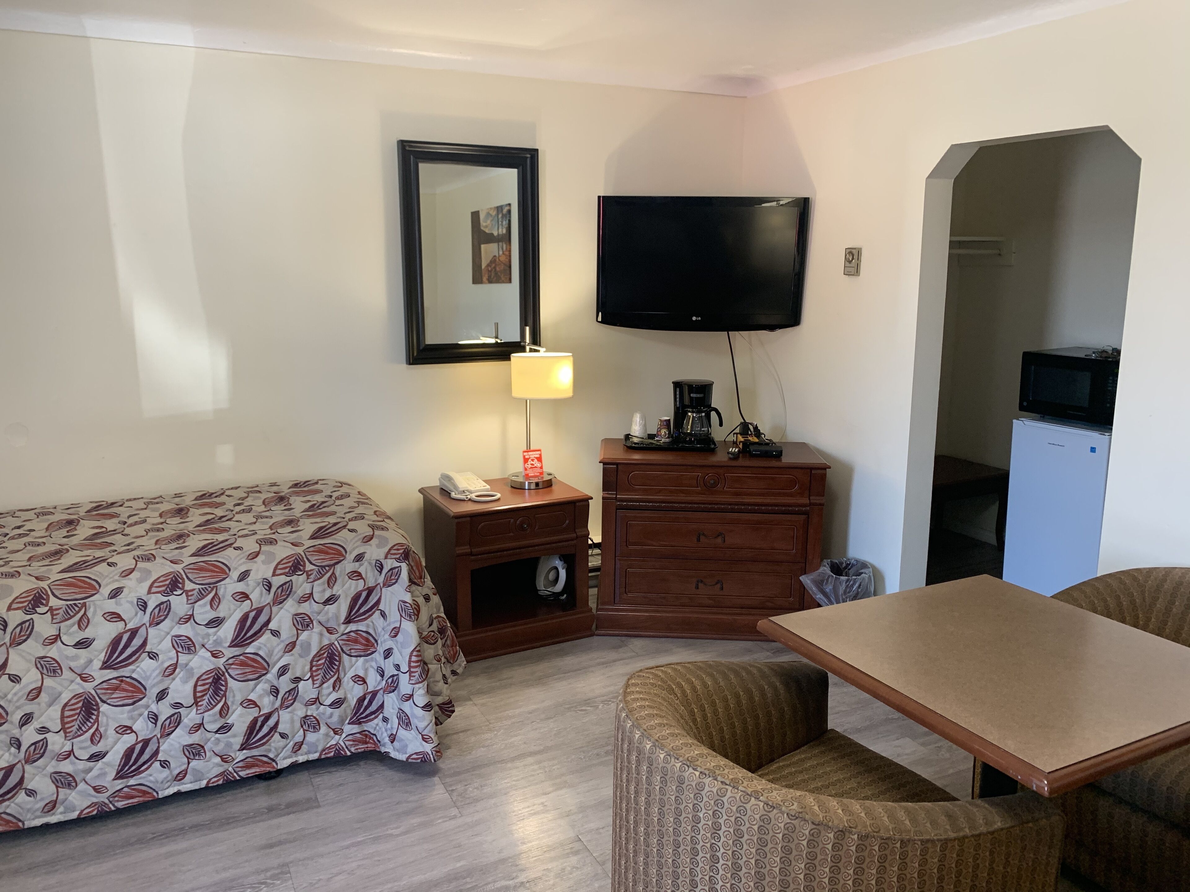 Une chambre d’hôtel équipée d’un lit, d’un bureau avec une lampe, d’une télévision, d’un four à micro-ondes et d’un réfrigérateur.