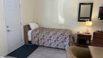 Una habitación de hotel con cama, escritorio, silla, lámpara de escritorio, teléfono y televisión.