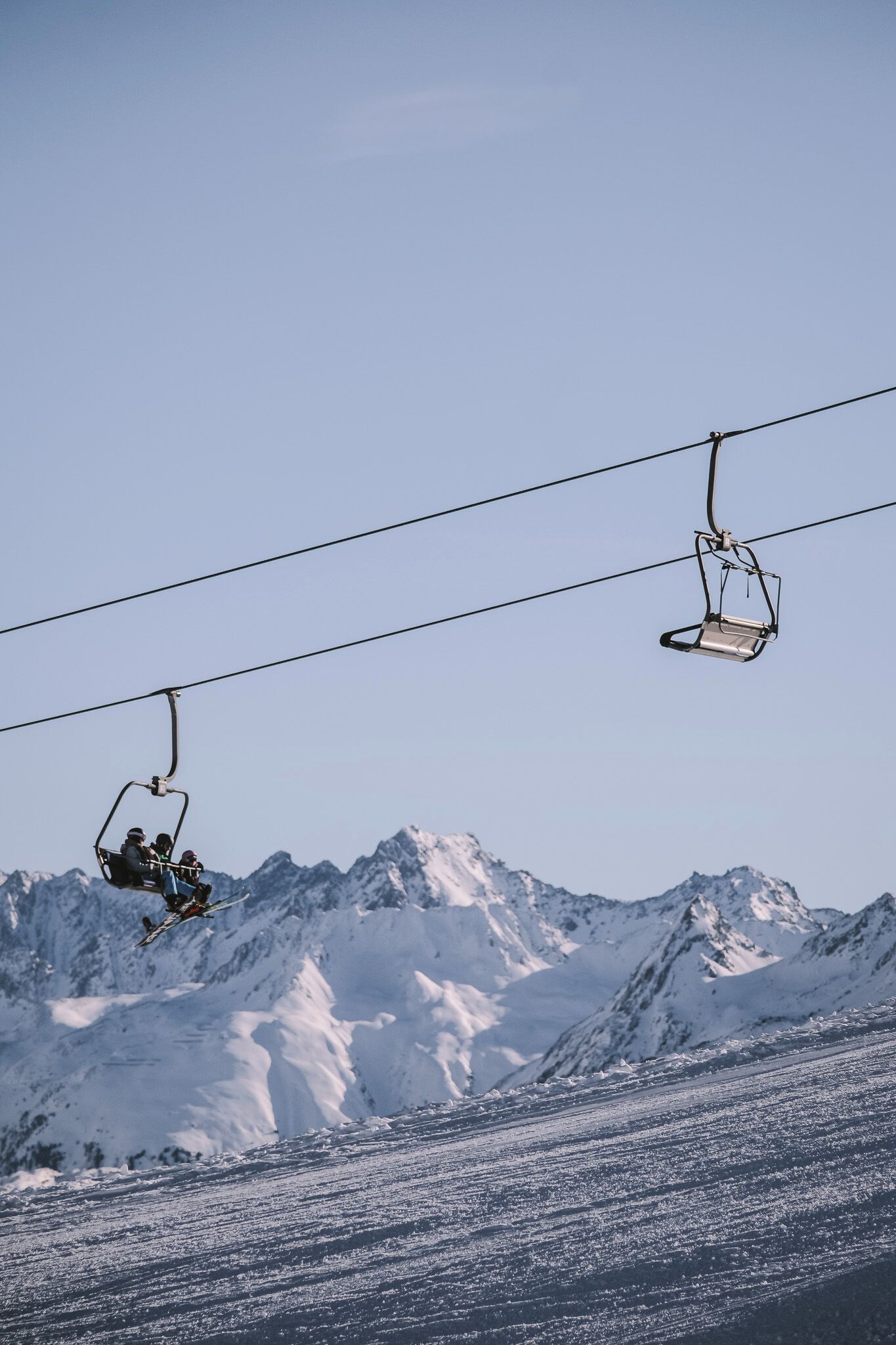 Un asiento de telesilla suspendido sobre una ladera nevada.
