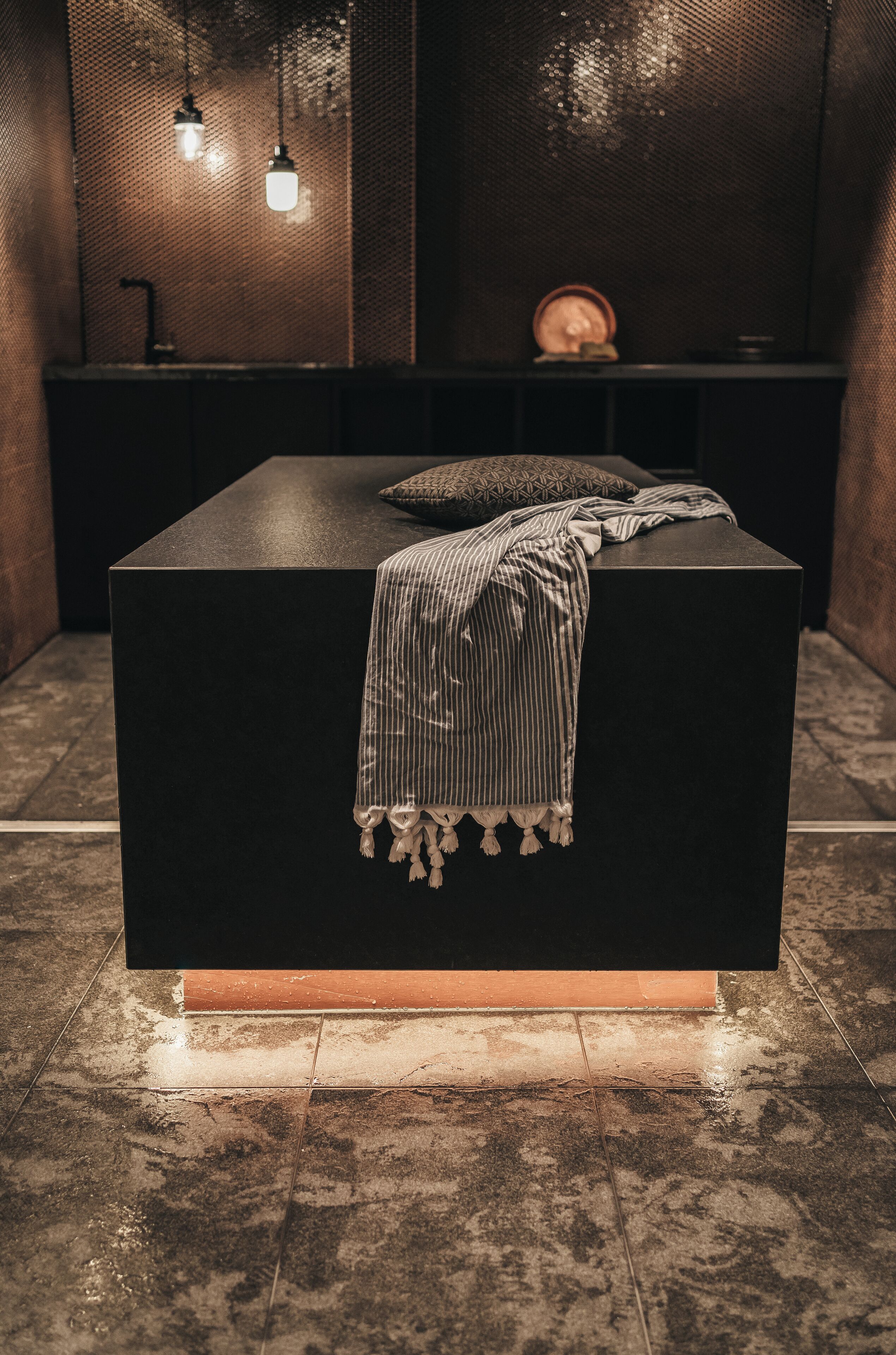 A modern bathroom with a black vanity, a striped towel, and two hanging pendant lights.