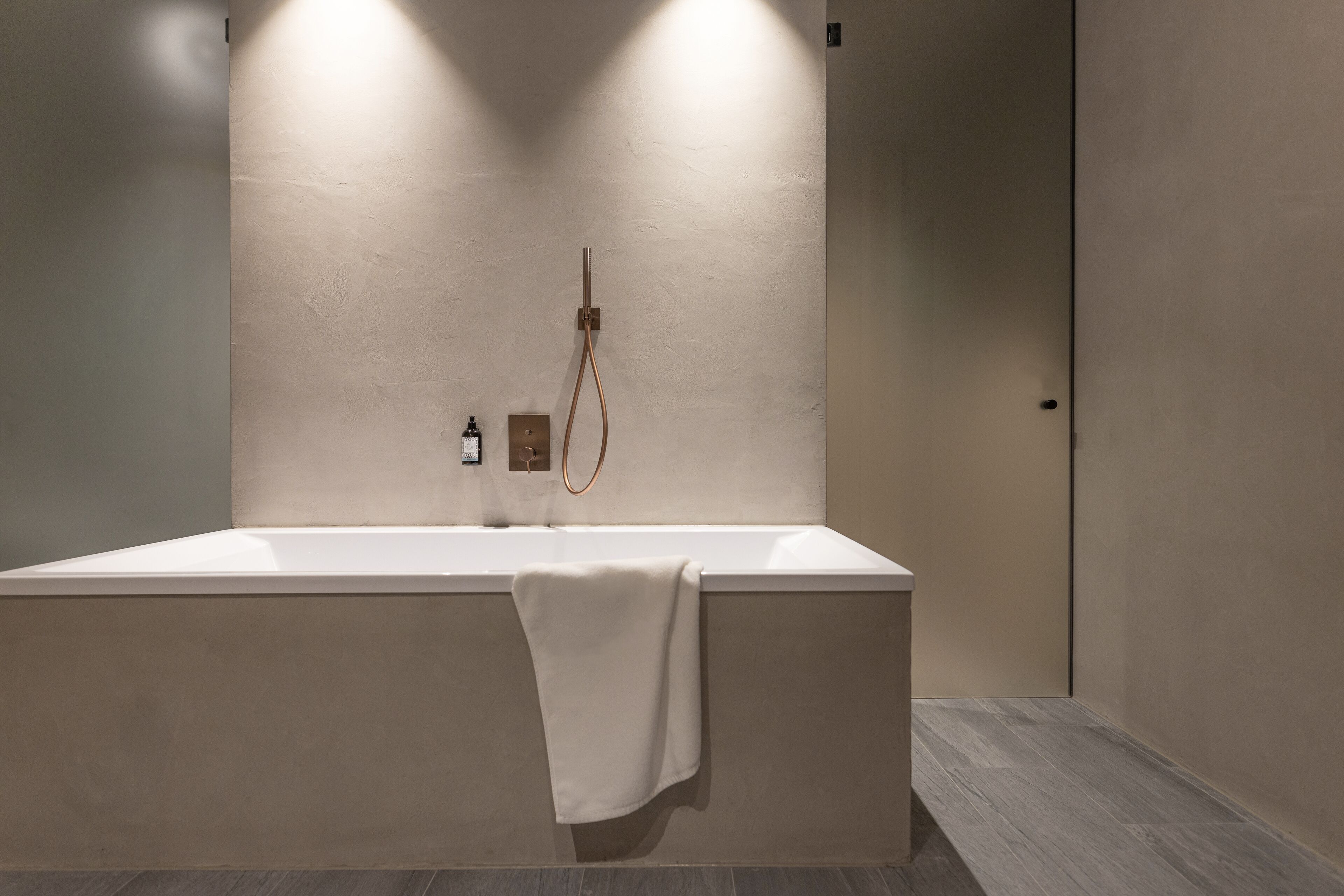Un baño moderno con una bañera grande, una toalla colgando y un cabezal de ducha en la pared.
