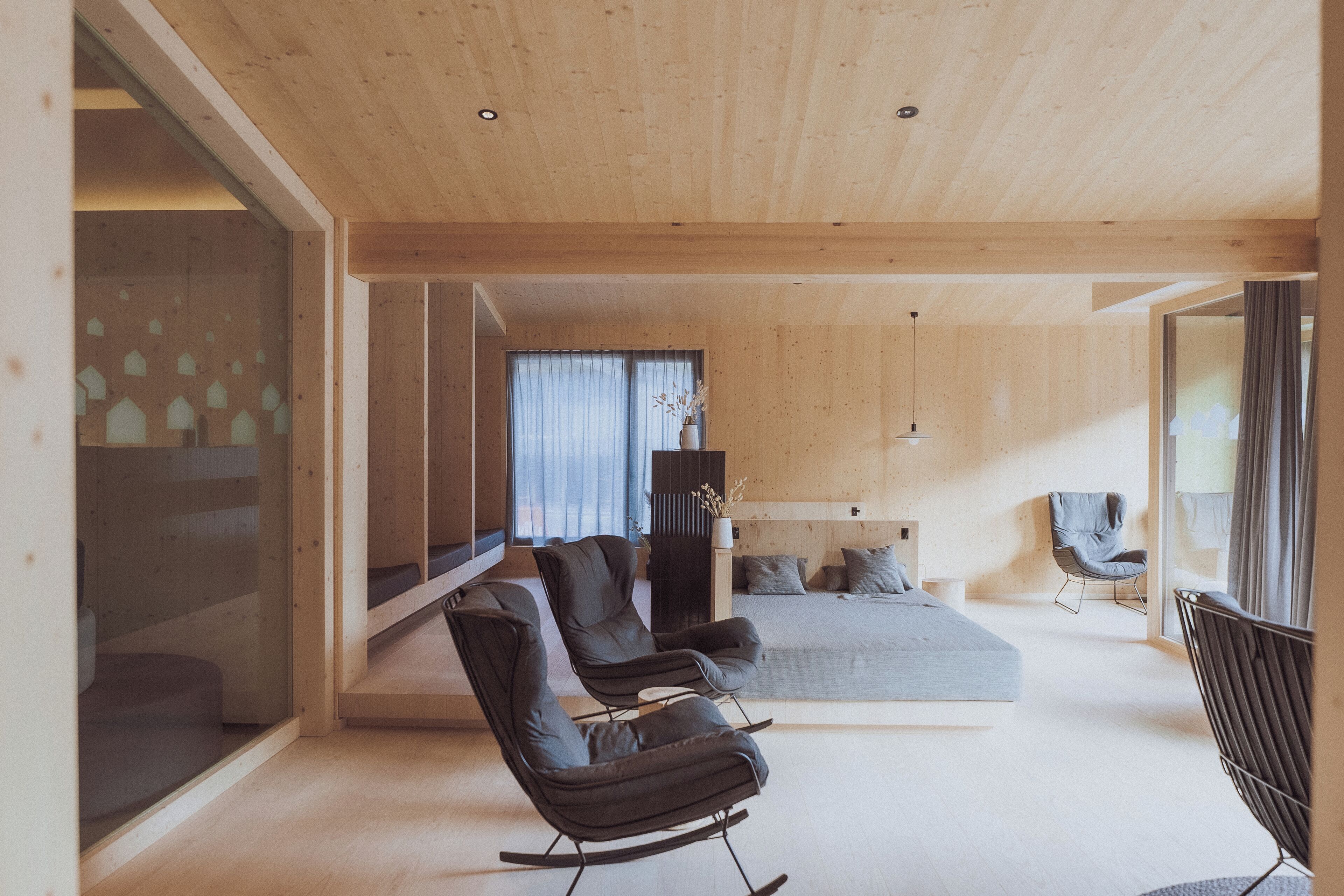Un interior moderno con techo de madera, un sofá, una cama y un comedor.