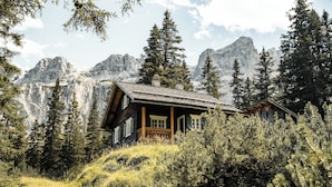 A wooden cabin with a balcony, surrounded by trees and mountains. - Amrai Suites (Schruns)